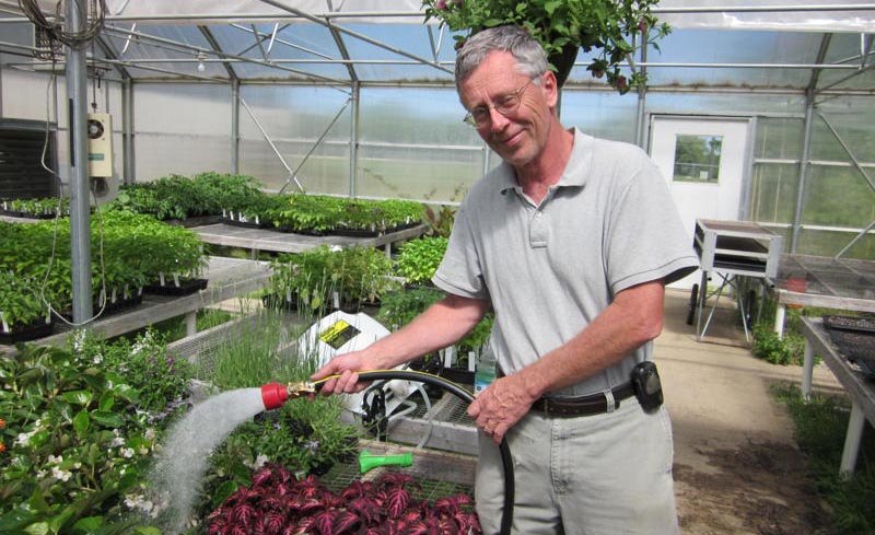 man stands watering plants