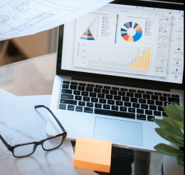 people standing near papers, glasses, and laptop on table