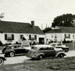 black and white photo of houses on street with cars parked