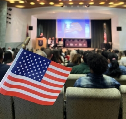 An American flag in the foreground of a naturalization ceremony at the Library.