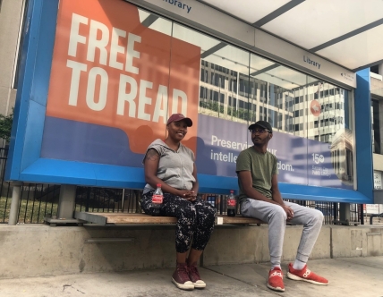 two people sit at streetcar stop