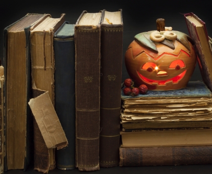 lit pumpkin and old books