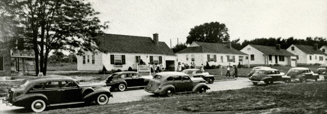black and white photo of houses on street with cars parked