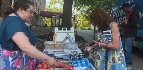 Library staffers show patrons books at a Bookmobile stop at Nowlin Apartments.
